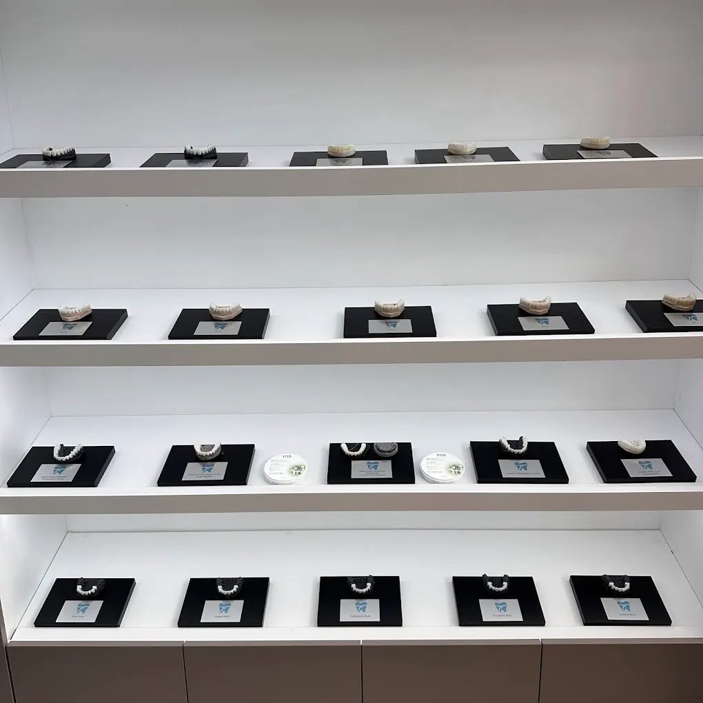 The shade and style library at Tantalya Dental Clinic — a lit wall of zirconia and E.max full-arch samples